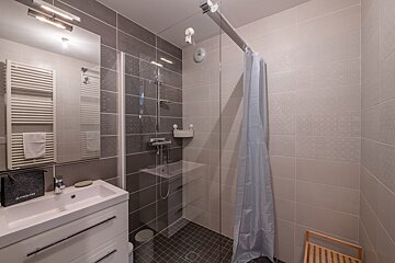 A bathroom with a walk in shower and a sink