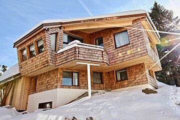 A snowy house with a white t on the side of it