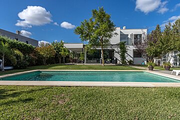 A house with a large swimming pool in front of it