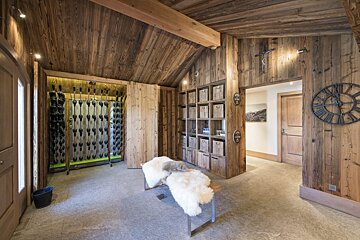 A clock with roman numerals hangs on a wooden wall