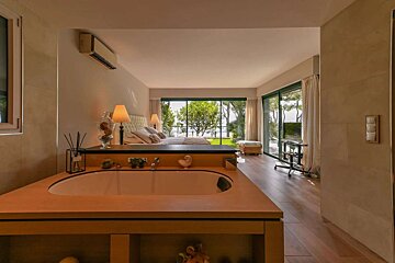 A bathroom with a bathtub and a bed in the background