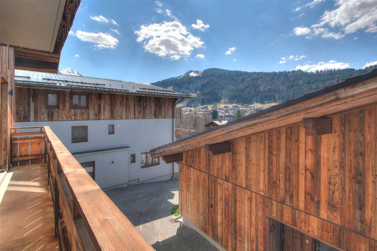 A balcony overlooking a wooden building with mountains in the background
