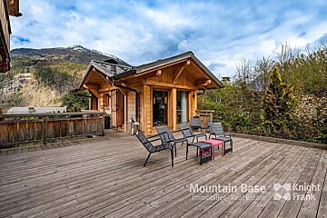 A wooden deck with chairs and a table that says mountain base on it