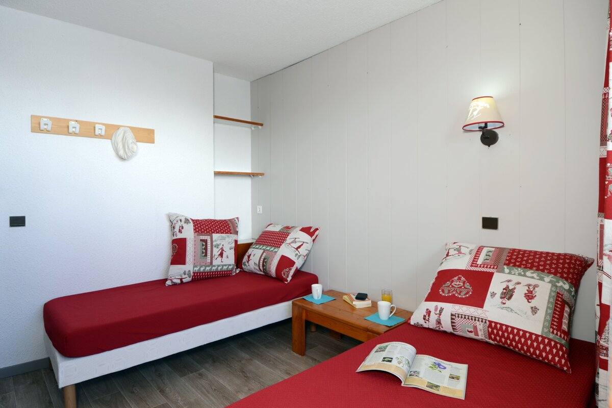 A bedroom with two beds and a table with a book on it