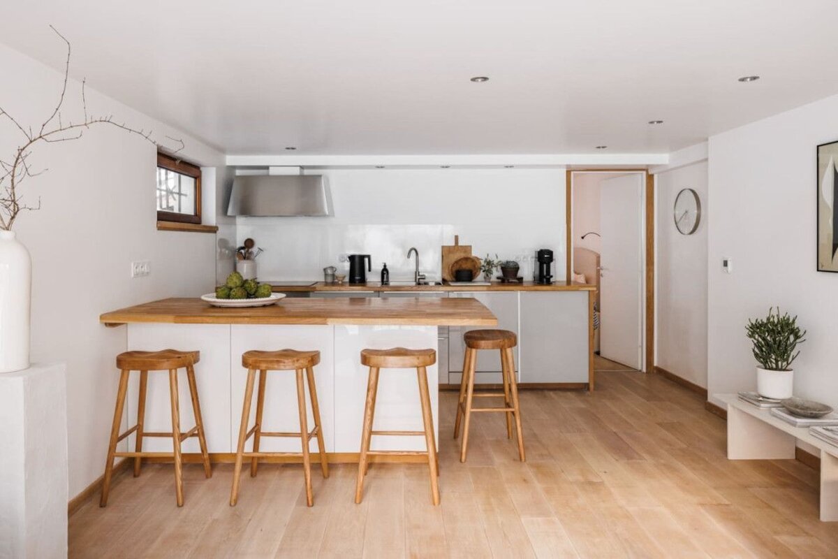 A kitchen with white cabinets and wooden stools