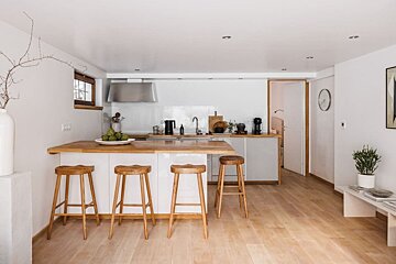 A kitchen with white cabinets and wooden stools