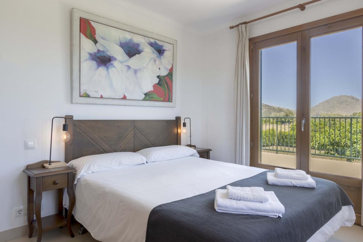 A bedroom with a wooden headboard and a painting on the wall above the bed