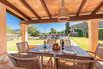 A bottle of wine sits on a table with plates and chairs
