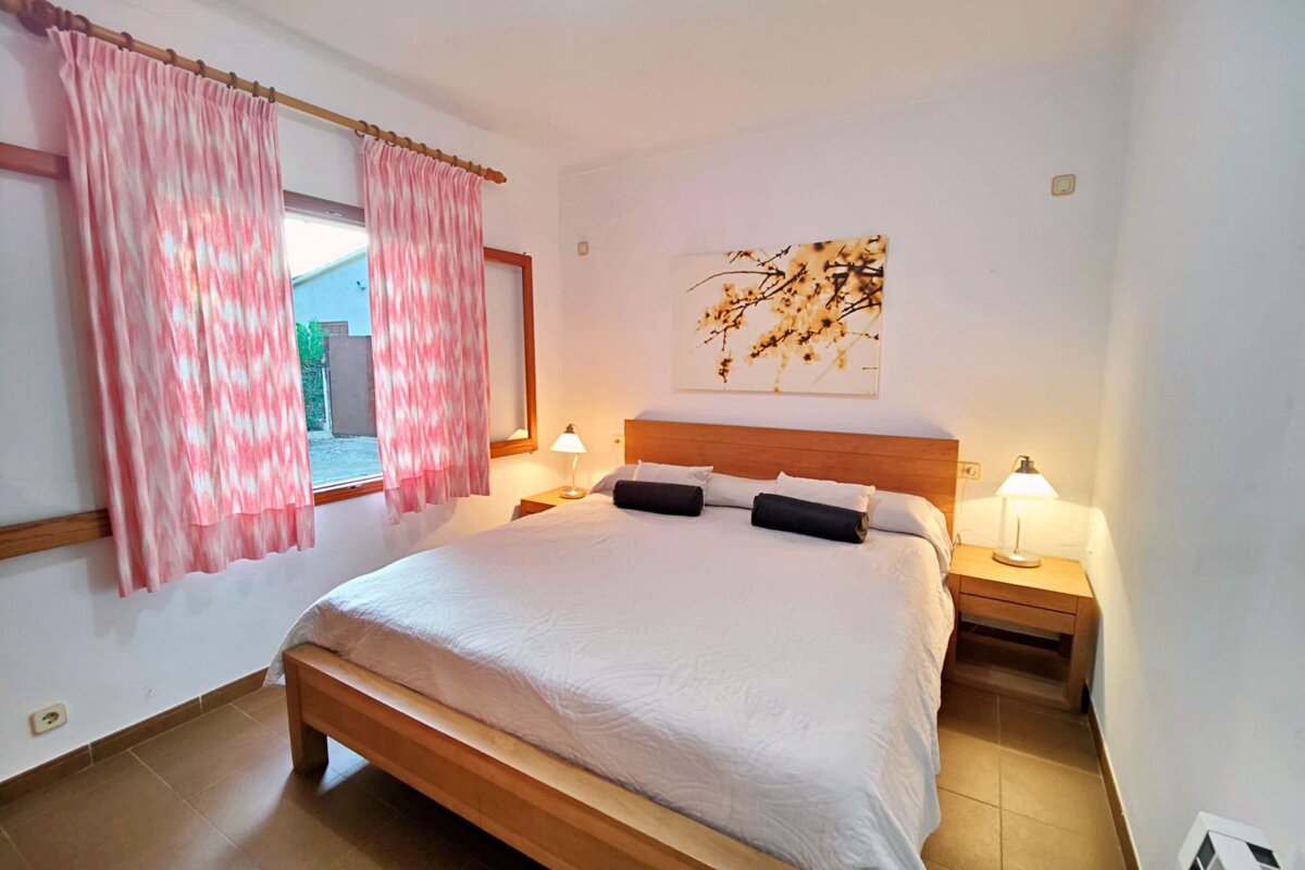 A bedroom with a painting on the wall above the bed