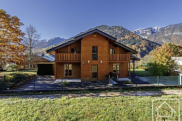 A large wooden house with mountains in the background