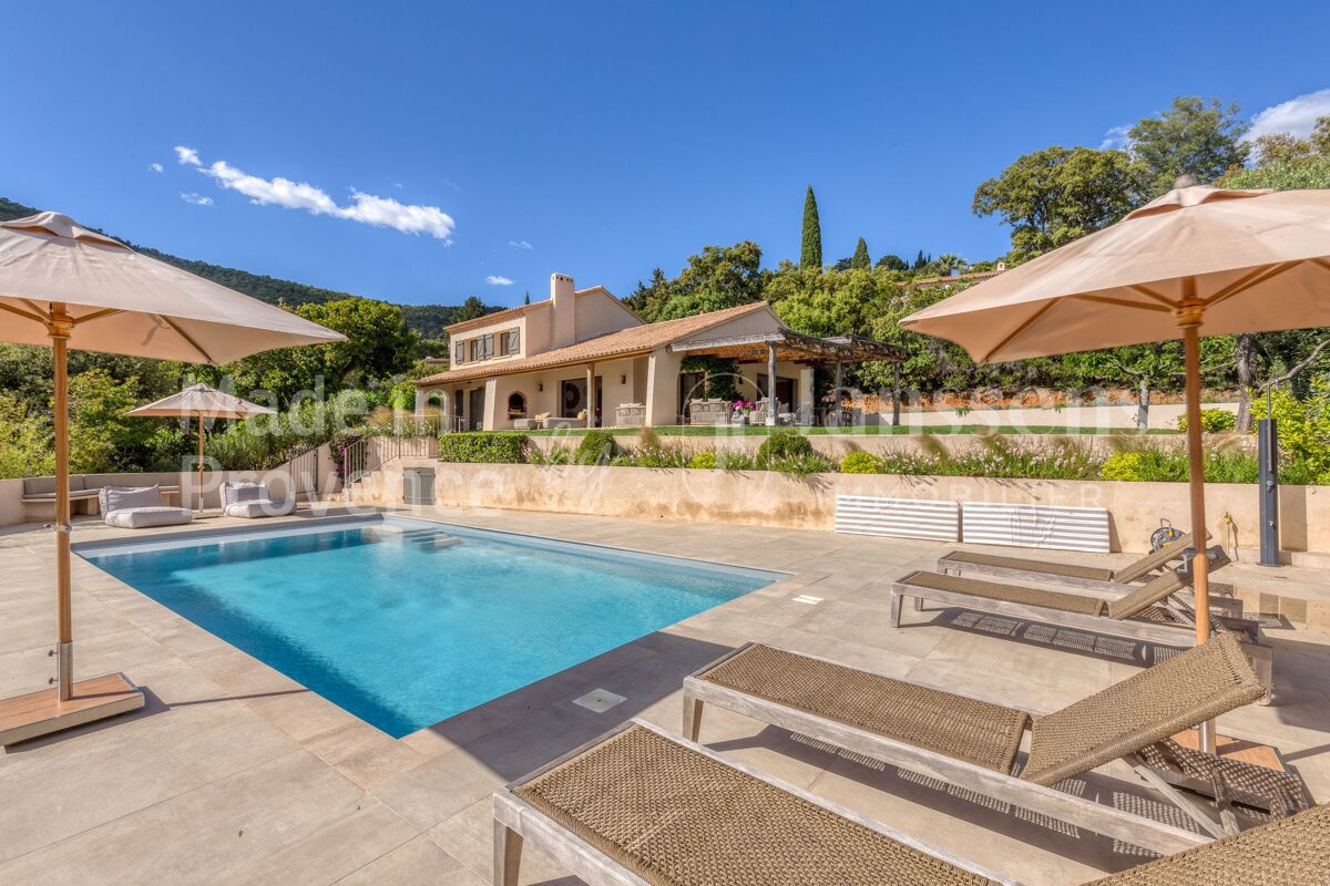A large swimming pool is surrounded by lawn chairs and umbrellas