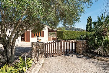 A wooden gate leads to a house with a stone wall