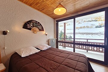 A bedroom with a bed and a fan on the wall