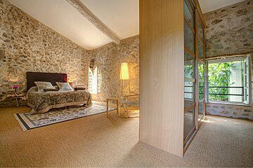 A bedroom with a stone wall and a large bed