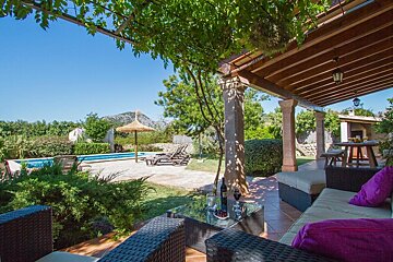 A patio with furniture and a table with a bottle of wine on it