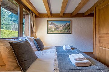 A bedroom with a painting on the wall above the bed