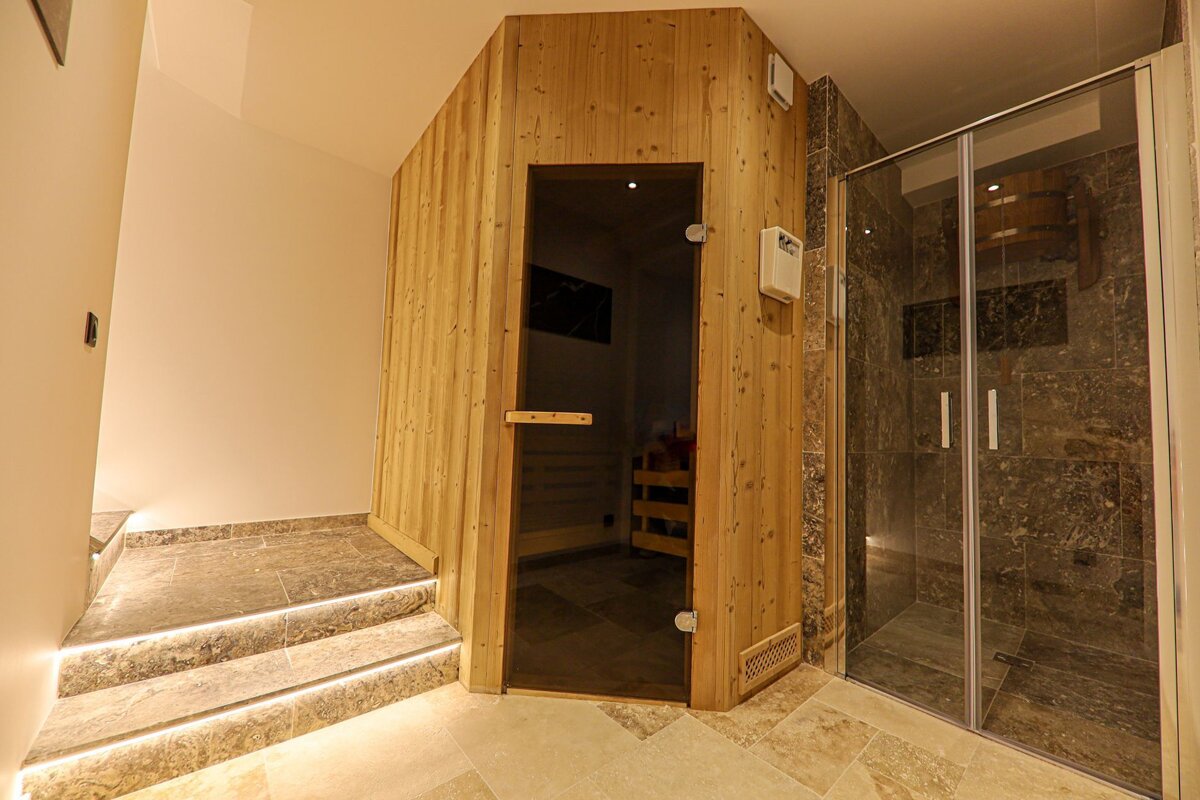 A wooden sauna with a glass door and stairs