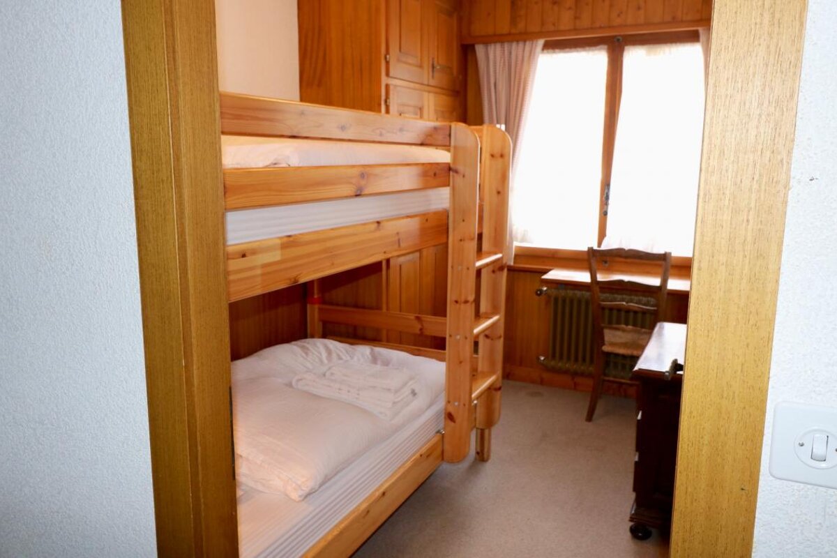 A bunk bed in a room with a desk and chair