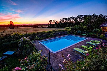 A large swimming pool surrounded by chairs and flowers at sunset