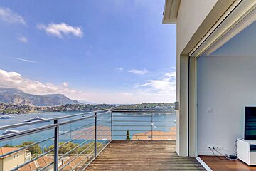 A balcony with a view of the ocean and mountains