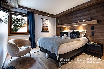 A bedroom with a bed and a chair and the words mountain base on the bottom
