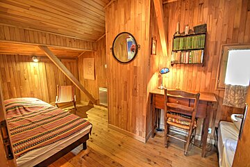 A wooden bedroom with a bed and a desk