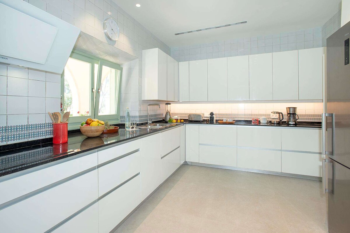 A kitchen with white cabinets and black counter tops
