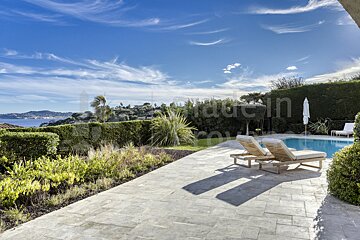 A patio with chairs and a swimming pool with the word jardin in the background