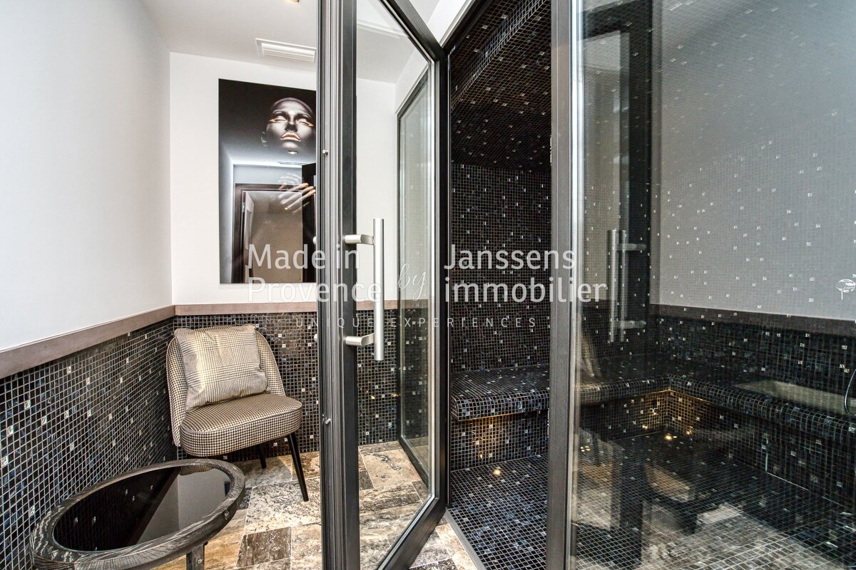 A bathroom with a chair and a glass door that says janssens immobilier