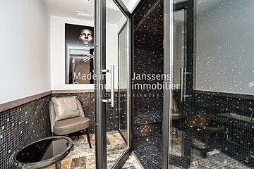 A bathroom with a chair and a glass door that says janssens immobilier