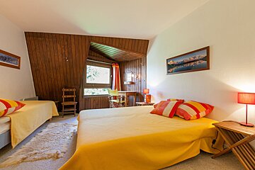 A bedroom with two beds and a painting on the wall