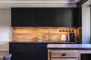 A kitchen with black cabinets and wooden counter tops