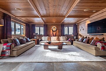 A living room with a wooden ceiling and a large flat screen tv