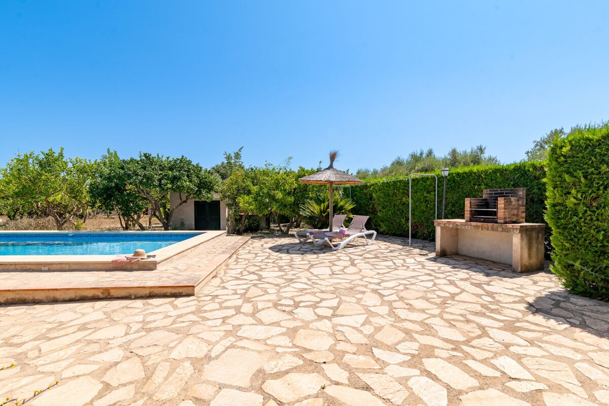 A stone patio with a swimming pool in the background