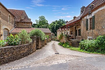 A narrow street with a stone wall between two houses