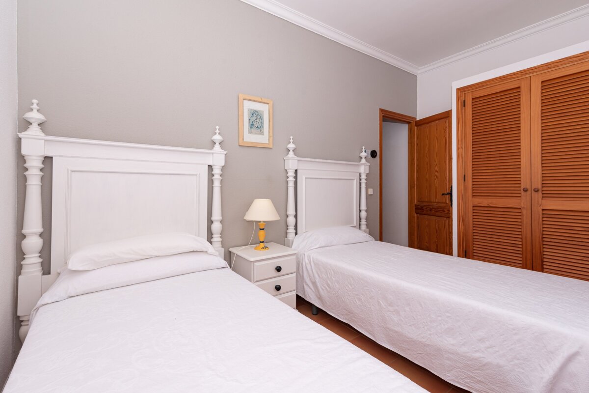 A bedroom with two beds and a lamp on the nightstand