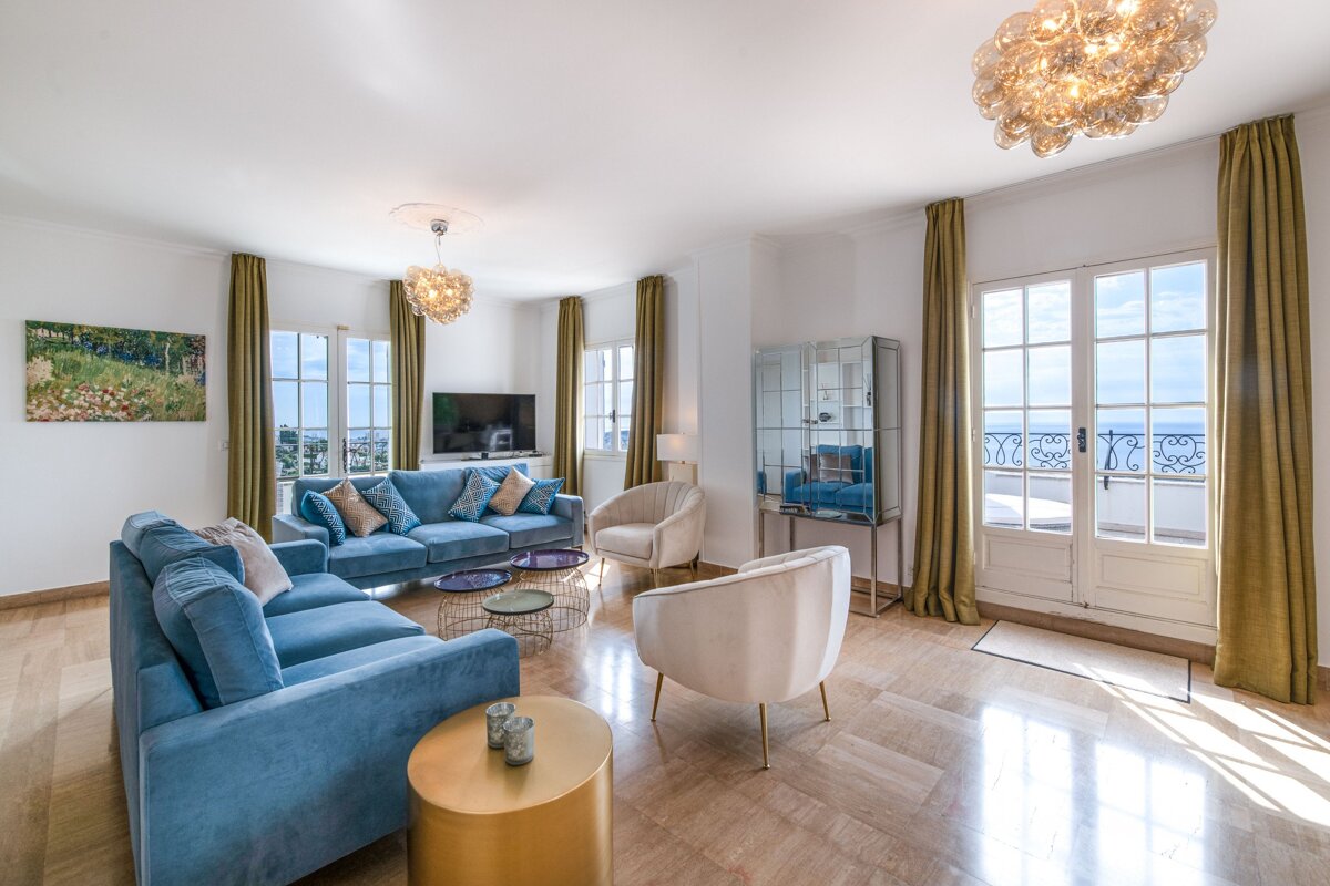 A living room with a blue couch and white chairs