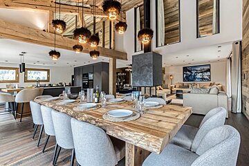 A dining room with a large wooden table and chairs