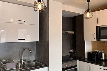 A kitchen with white cabinets and black counter tops