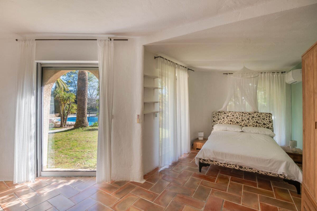 A bedroom with a canopy bed and a sliding glass door