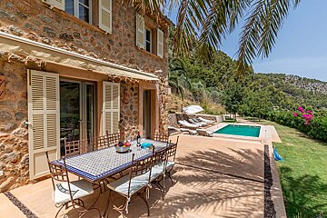 A patio with a table and chairs and a pool in the background