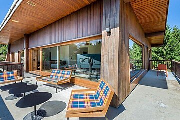 A balcony with chairs and tables in front of a house