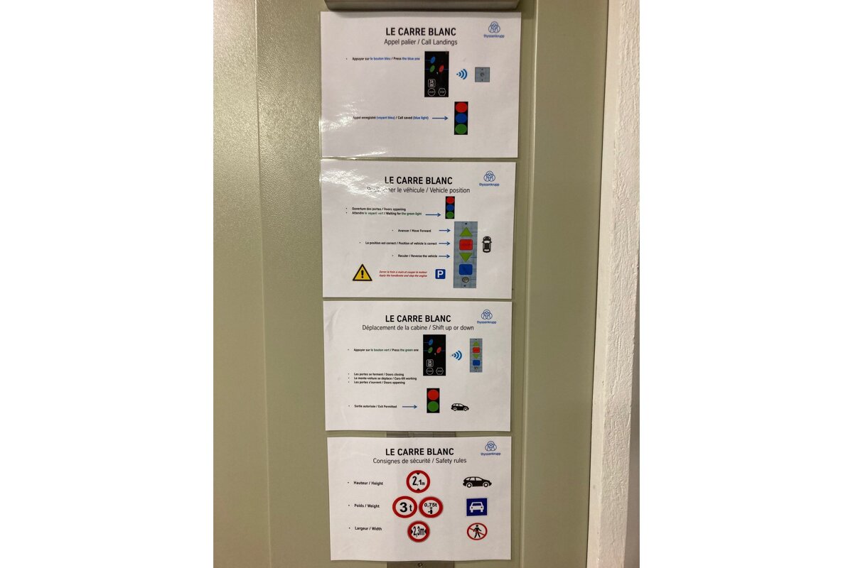 Four signs on a wall one of which says le carre blanc