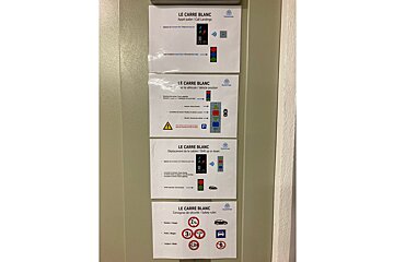 Four signs on a wall one of which says le carre blanc