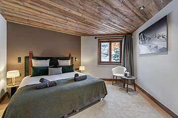 A bedroom with a king size bed and a chair