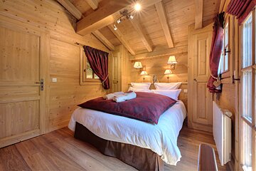 A wooden bedroom with a bed and a window