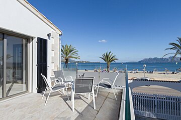 A balcony with a table and chairs overlooking the ocean