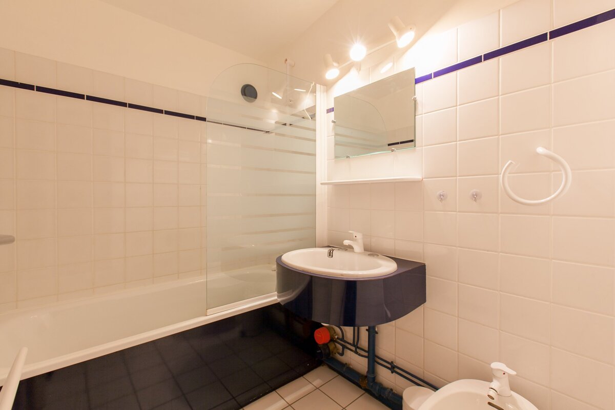 A bathroom with white tiles and a blue sink