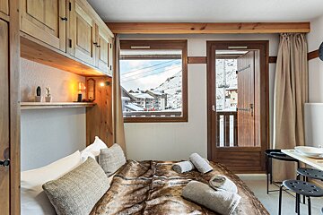 A bedroom with a bed and a window with mountains in the background