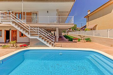 A swimming pool in front of a house with stairs leading up to it